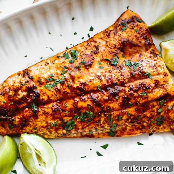A white plate with chili lime trout and lime wedges