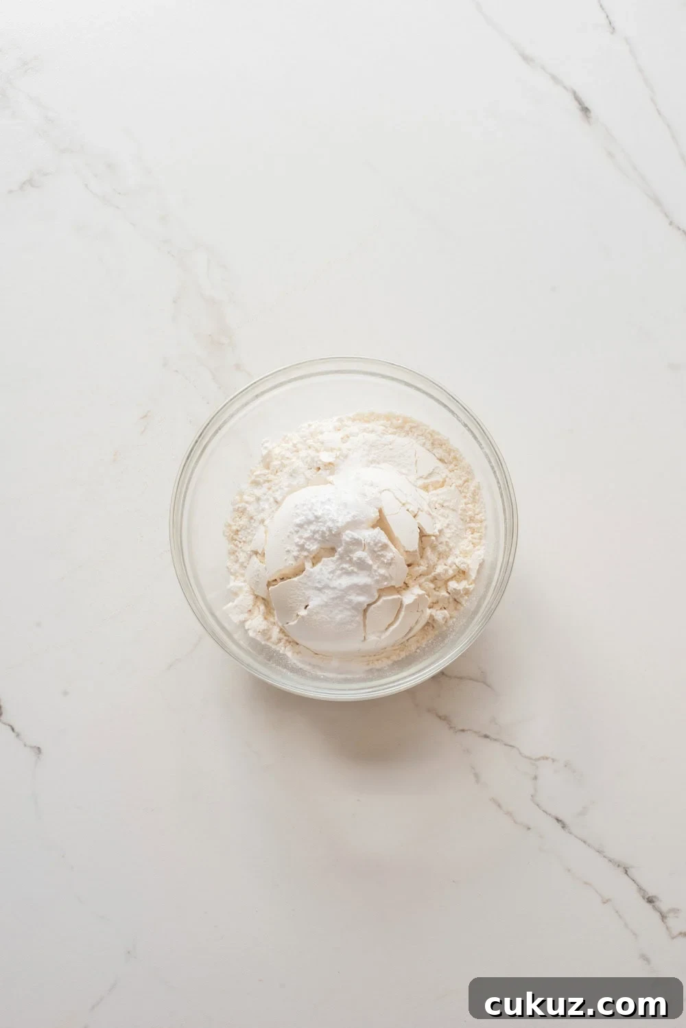 Dry ingredients for chocolate chip cookies in a glass bowl.