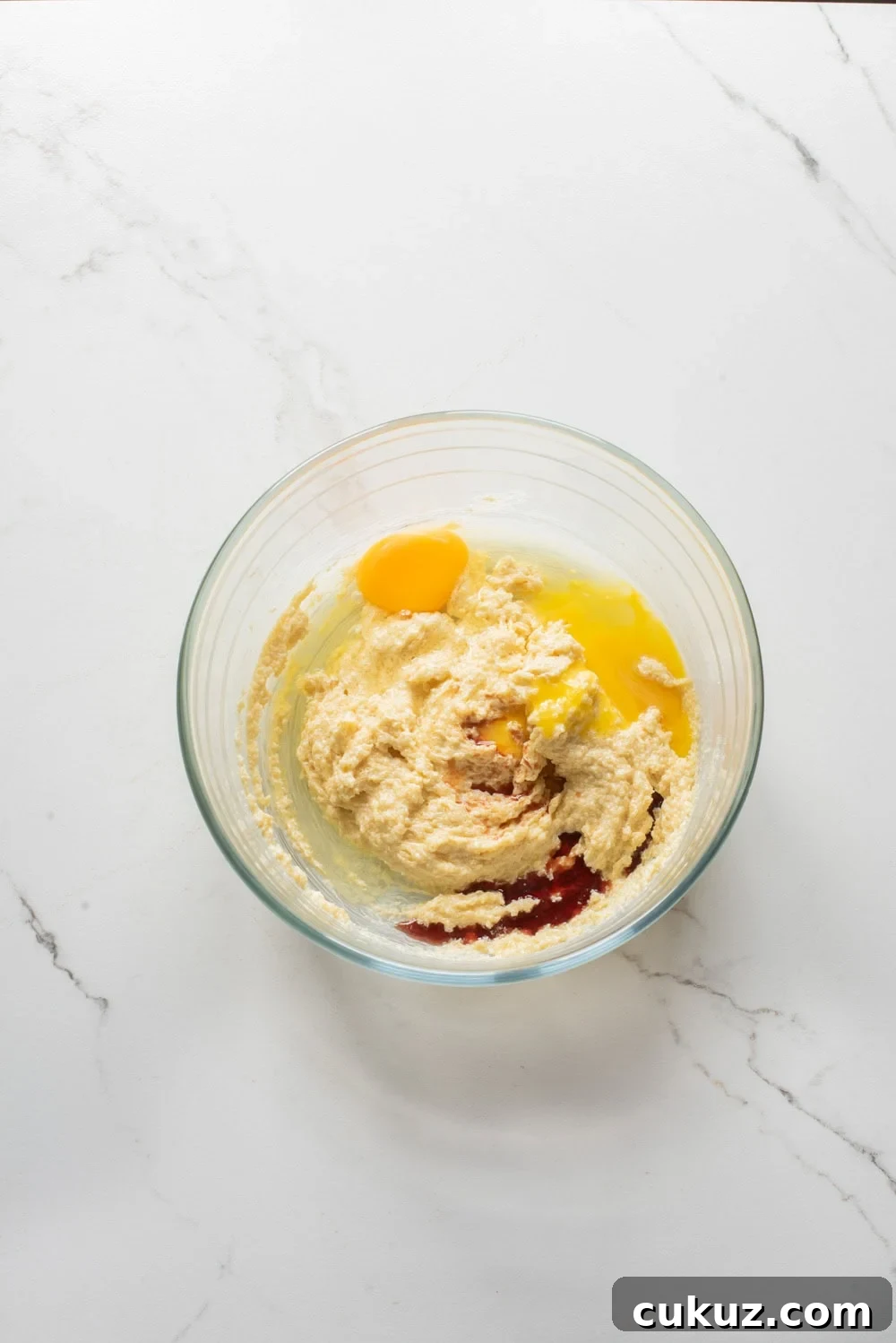 Egg and vanilla added to the butter and sugar mixture in a mixing bowl.