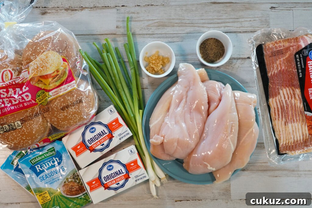 Slow cooker crack chicken ingredients sesame seed buns, ranch seasoning, cream cheese, green onions, garlic, black pepper, bacon and chicken breasts.