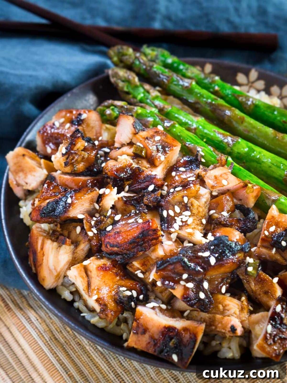 Sticky Teriyaki Grilled Chicken Bowl with Jasmine Rice 3 Angled view of grilled teriyake chicken and asparagus over rice and garnished with sesame seeds - Hostess At Heart