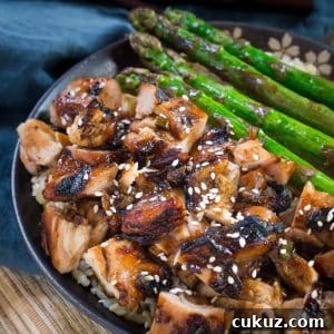 Sticky Teriyaki Grilled Chicken Bowl with Jasmine Rice 5 An angled image of a bowl filled with teriyaki glazed chicken and grilled asparagus sitting over brown rice. Hostess At Heart