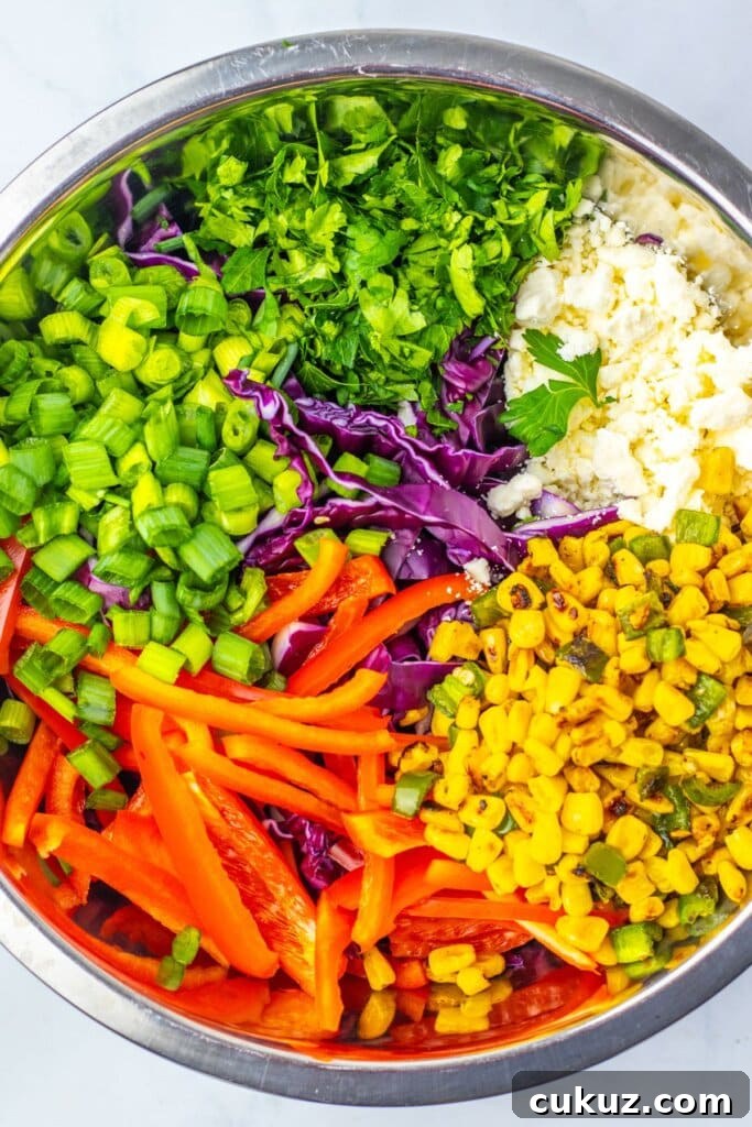 Salad ingredients added to a large stainless steel bowl.