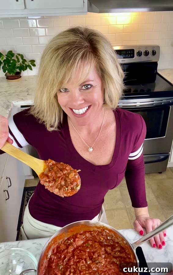 Jennifer holding a wooden spoon of red sauce