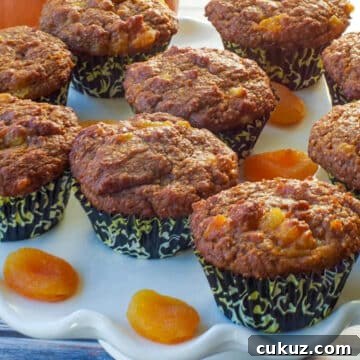 healthy bran pumpkin muffins on a white cake platter with dried apricots