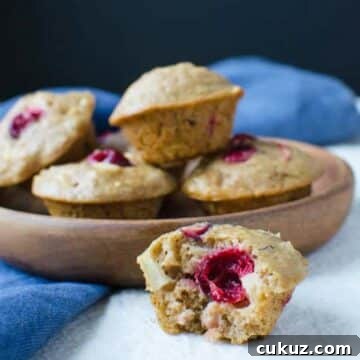 fruit and nut bran muffin with middle of muffin showing and bowl of more muffins in the background