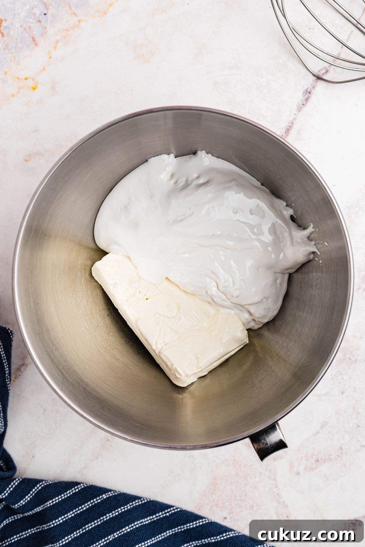 A block of cream cheese and marshmallow creme in a silver mixing bowl.