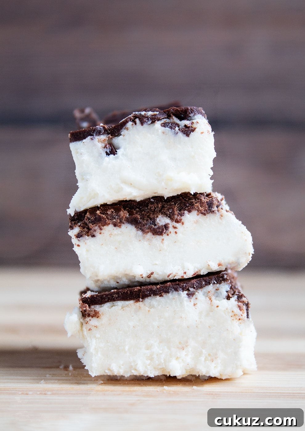 three keto salted caramel fat bomb bars stacked on top of each other in front of dark wood